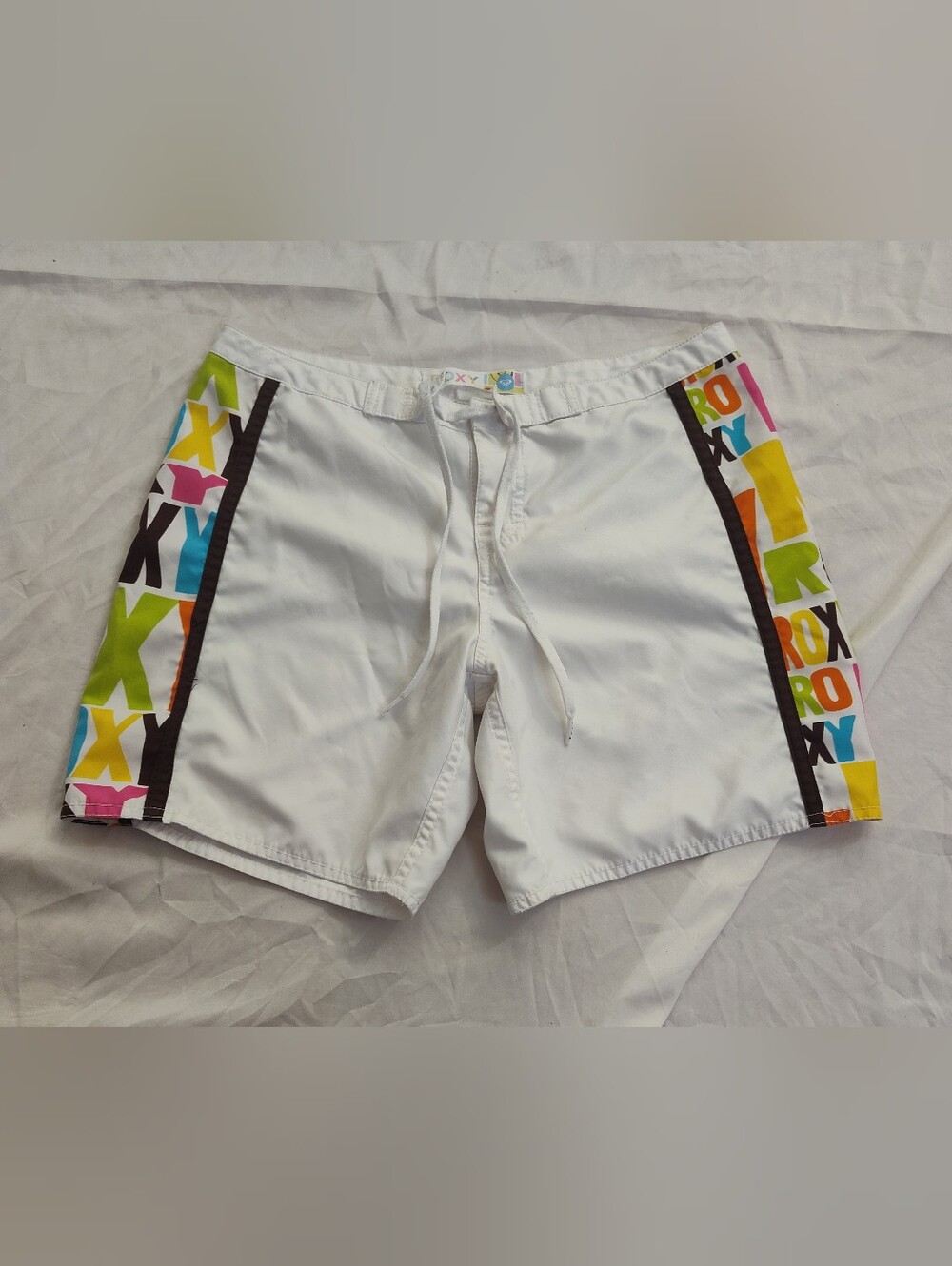Roxy Woman's White Board Shorts with Multicolor 'ROXY' text on side panels.